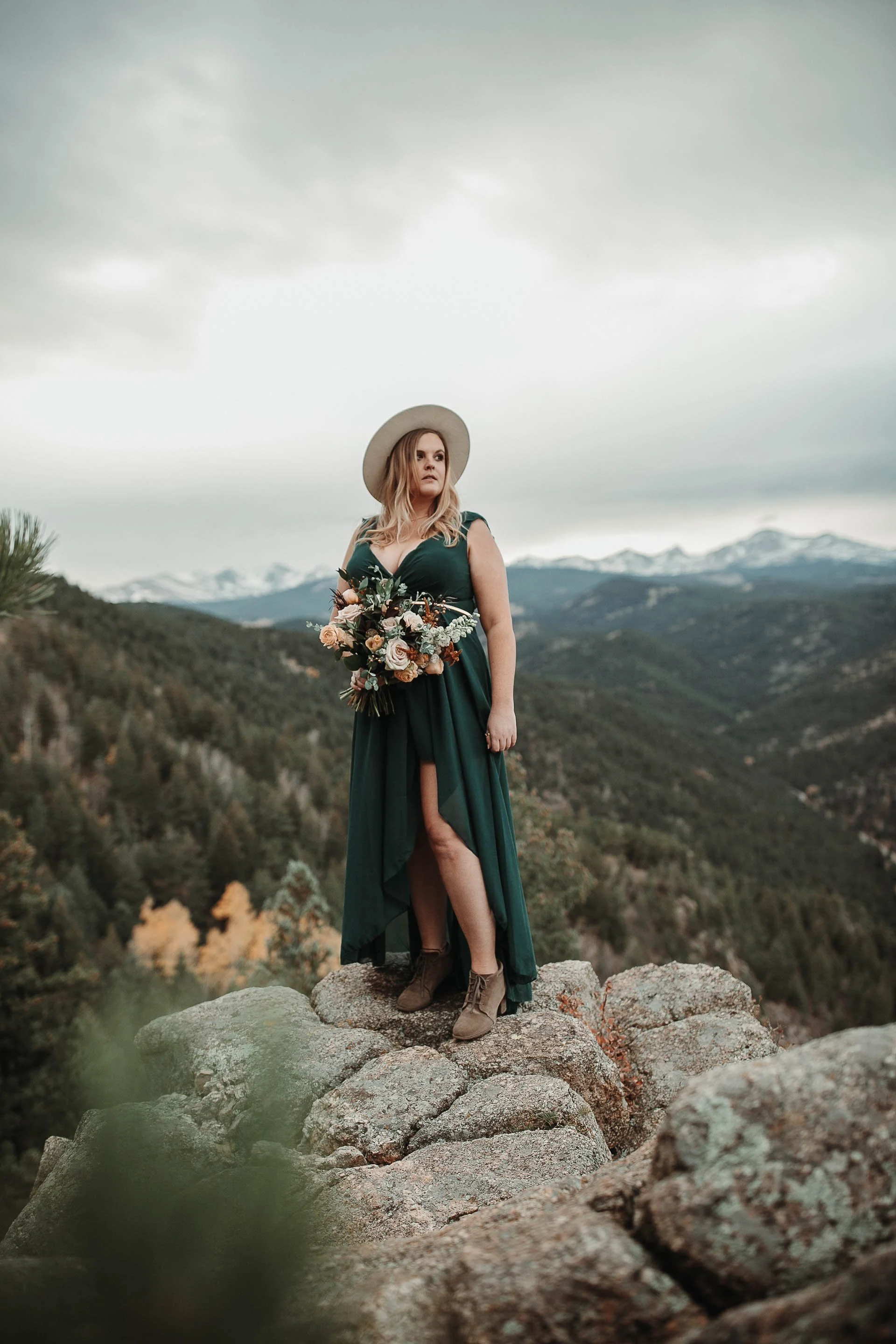 Rocky Mountain Elopement photo of Bride on cliffside with the snowcap mountains behind her