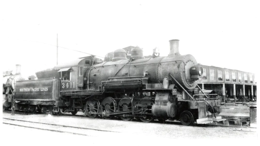 This engineer’s view of Southern Pacific 3411 illustrates several details of the C-19 class 2-8-0 and the back shop area of the El Paso’s shop.  The 3411 received this type of valve assembly when the locomotive was superheated in El Paso by the EP&SW