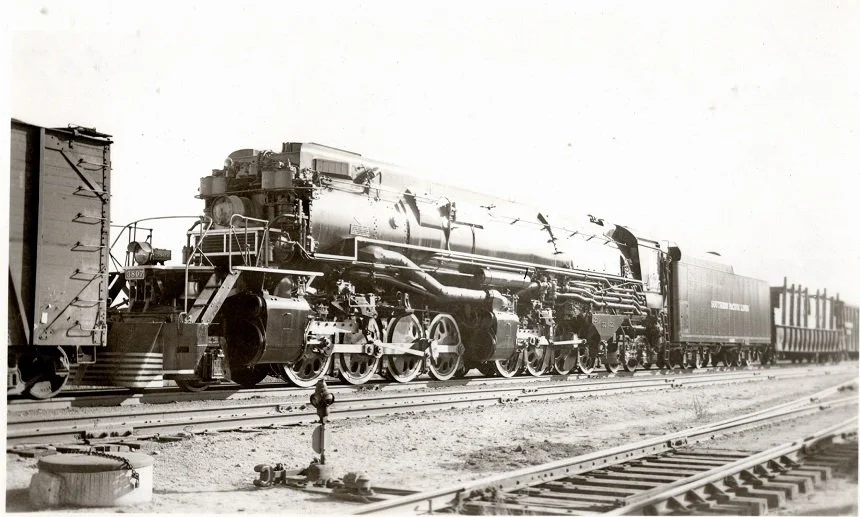 Here we see the Fireman’s side of Southern Pacific 2-8-8-4, AC-9 Class, #3807 while the locomotive was enroute from the factory to El Paso for delivery for set up for the SP.  In the cab you can see the factory messenger sent to ensure the safe shipm