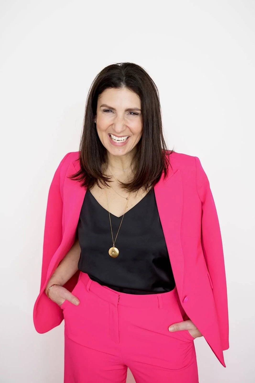 Michelle Pollack, Executive Life and Leadership Coach for Women, is wearing a pink pantsuit & beaming!