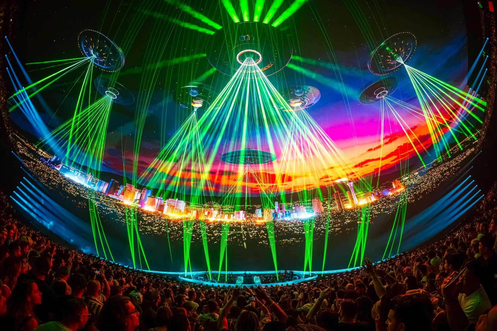 Wide shot of content on Sphere's media plane of UFOs shooting green lasers down onto the Las Vegas Strip