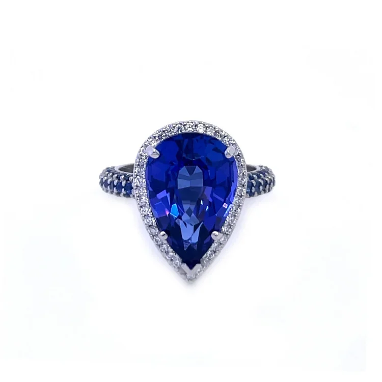 Ring with a large pear-shaped tanzanite gemstone surrounded by small diamonds, set on a white gold band with small sapphire gems.