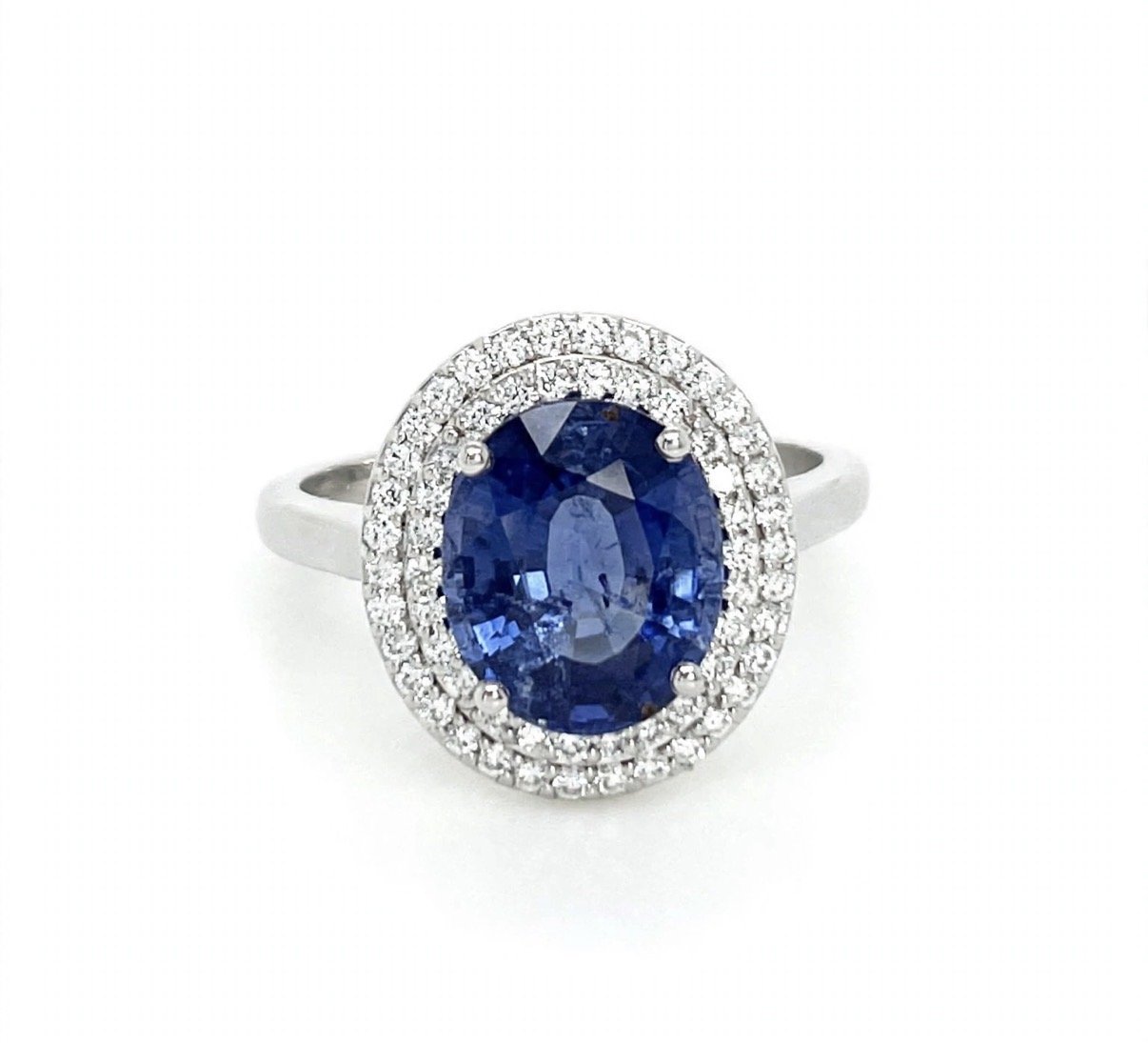 White gold ring with a large oval sapphire gemstone surrounded by small diamonds.