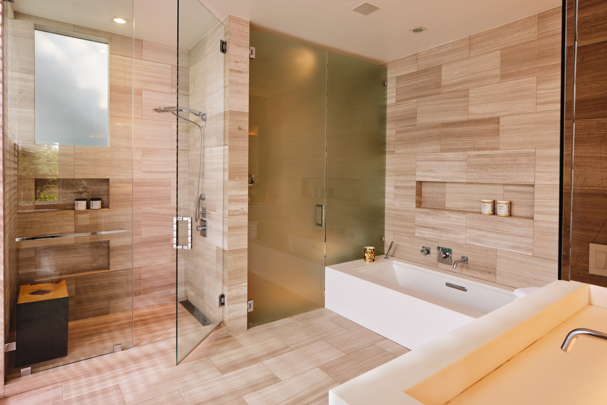 Modern bathroom with a glass shower enclosure, a bathtub, wood-textured wall tiles, and a frosted glass partition.