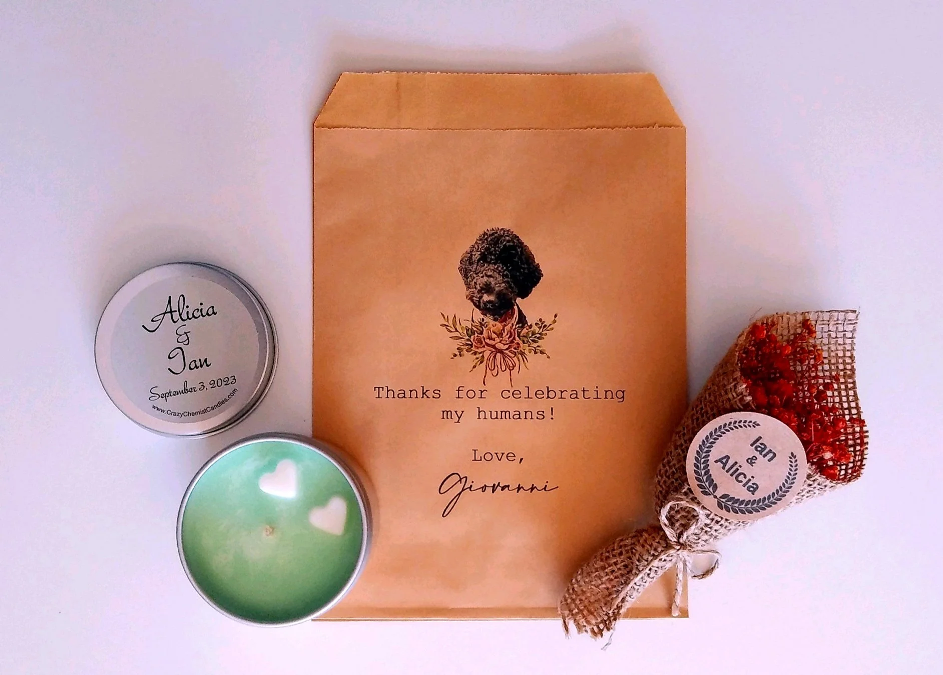 A collection of personalized candles and a thank you card. The candles are round, with one in light green featuring white heart shapes, and another in silver with a descriptive label. The thank you card has a vintage photo of a girl with flowers, and