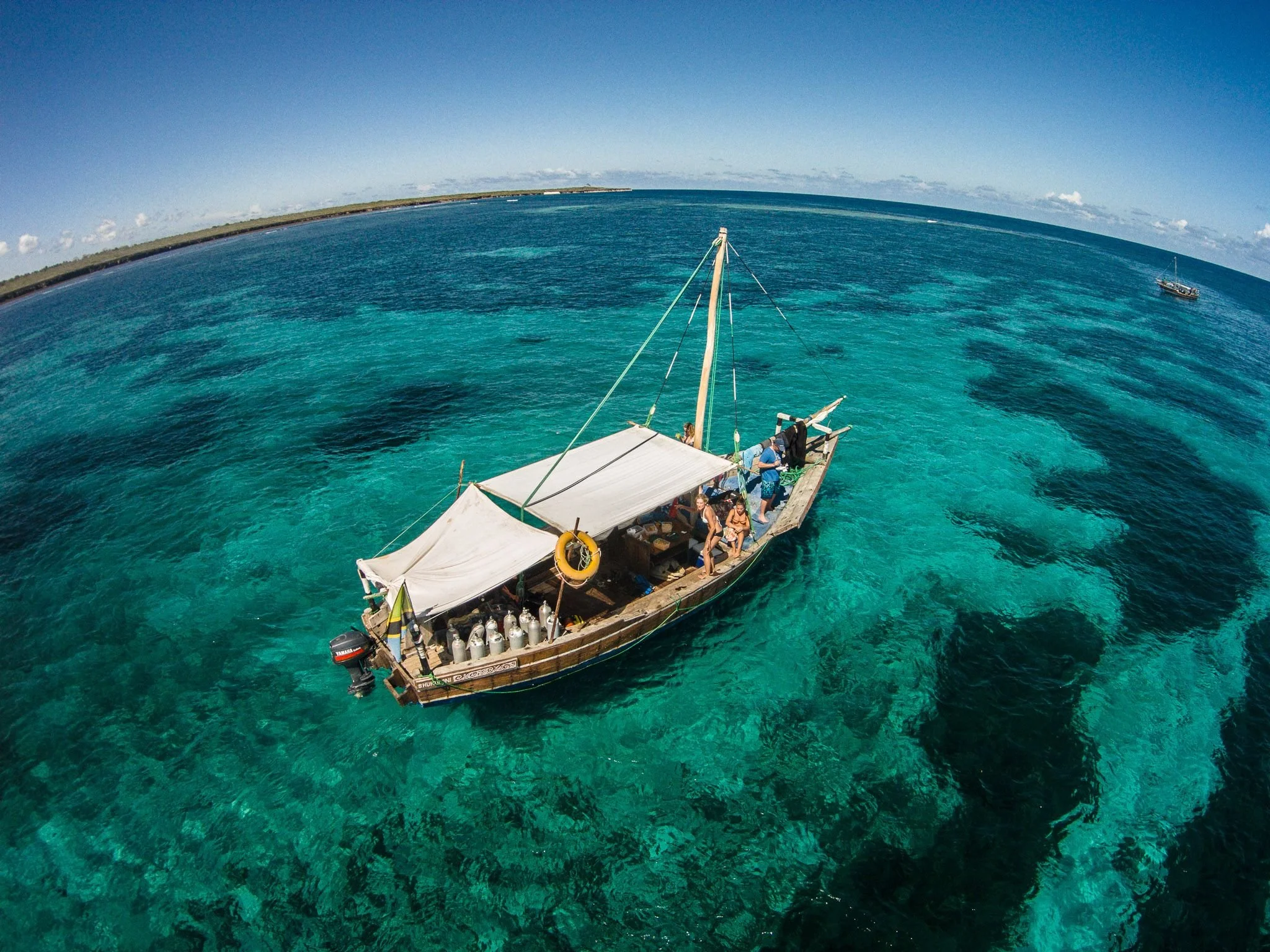 Båt med dykkerutstyr og elever i krystallklart vann i Mafia Island