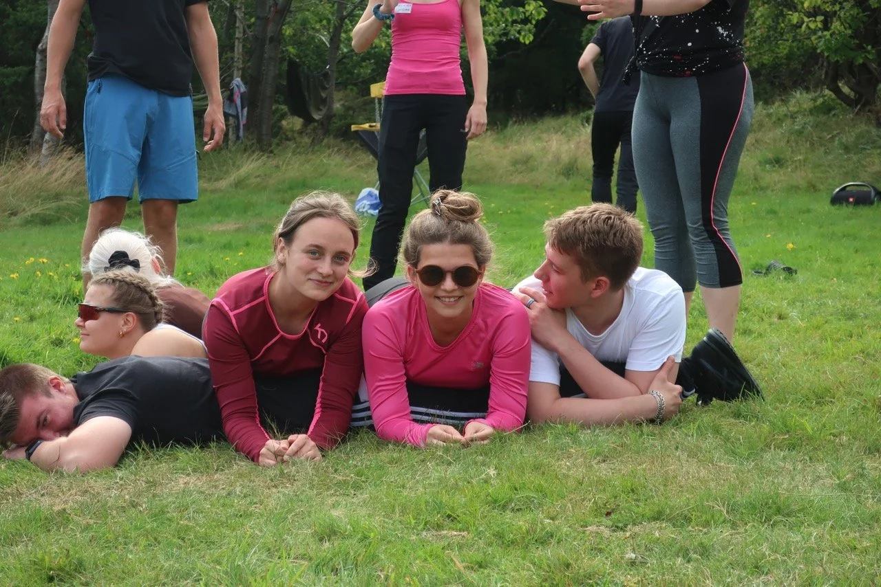three young adults from different countries laying on the grass in the southern coastline of Norway.