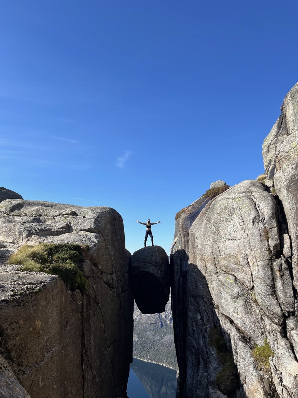 Girl standing on Kjearagsbolten high below a beautiful fjord.