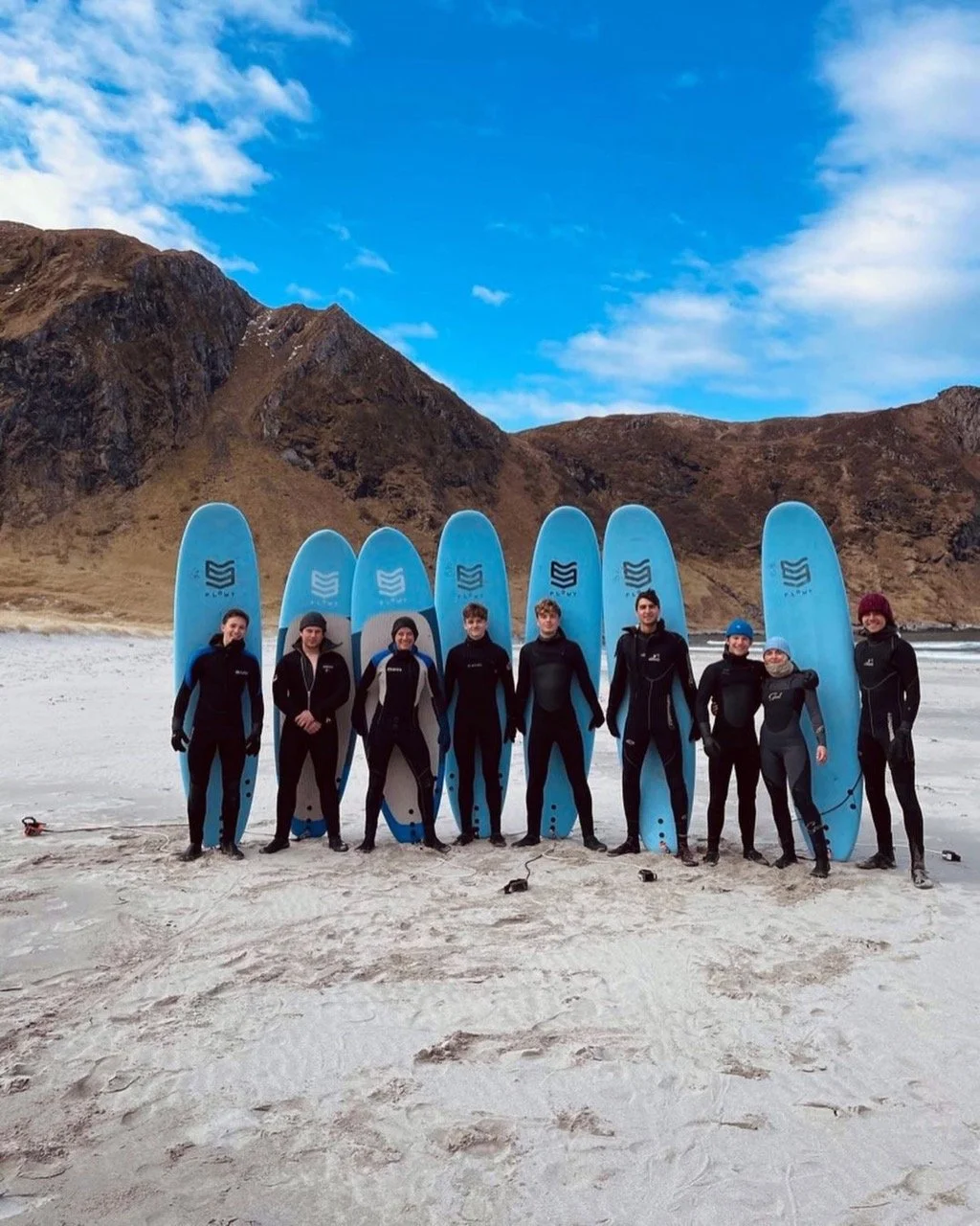Gjeng fra linja klatring, dykk og surf på stranda med surfebrett på Hoddevika