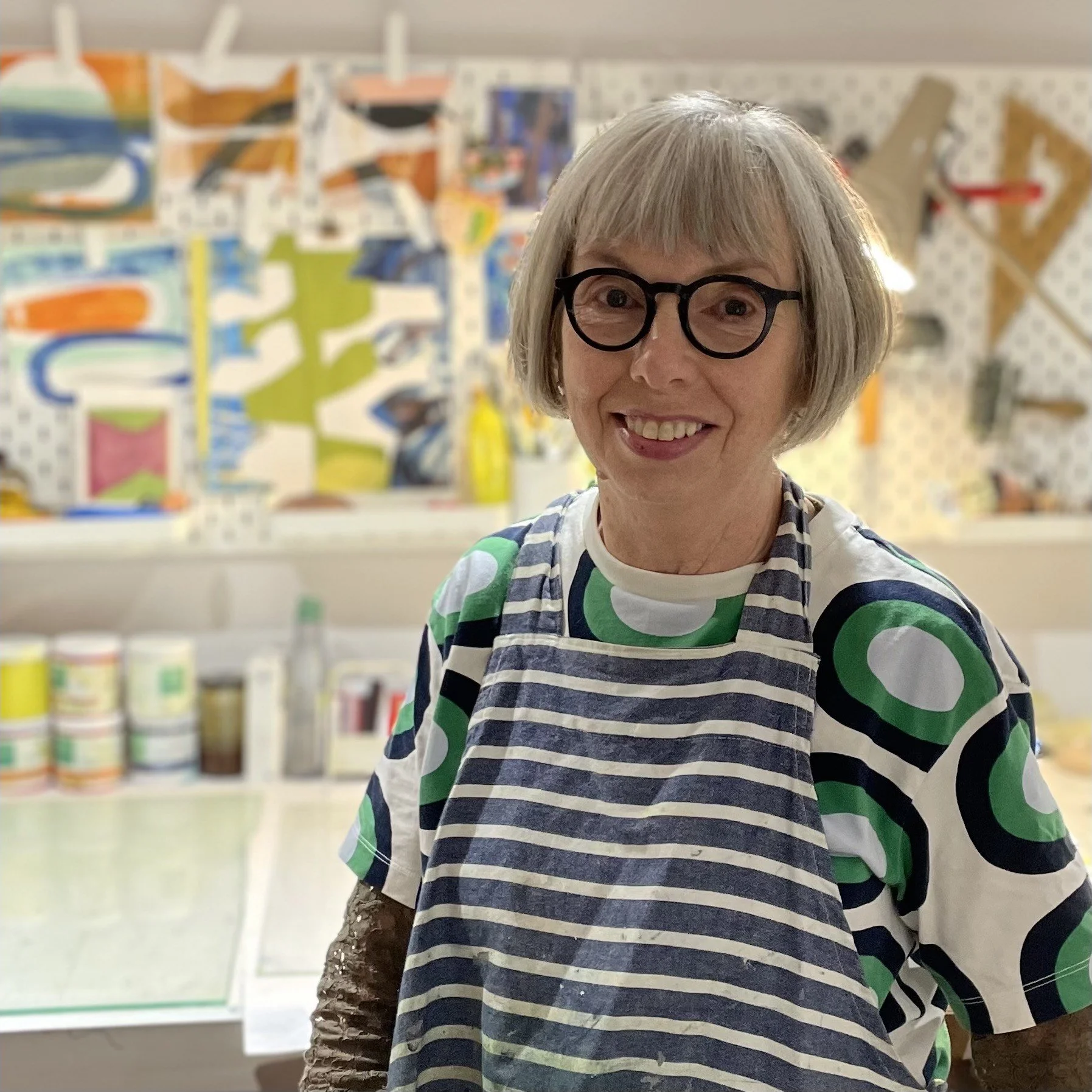 Shirely Stevenson standing in her studio with her colourful collagraph prints behind her