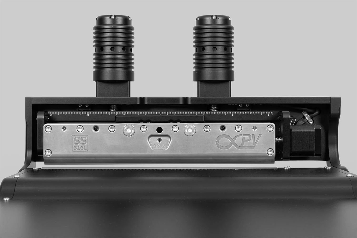 Close-up of a piece of industrial machinery with two black cylinders on top and a silver mechanical component in the center.