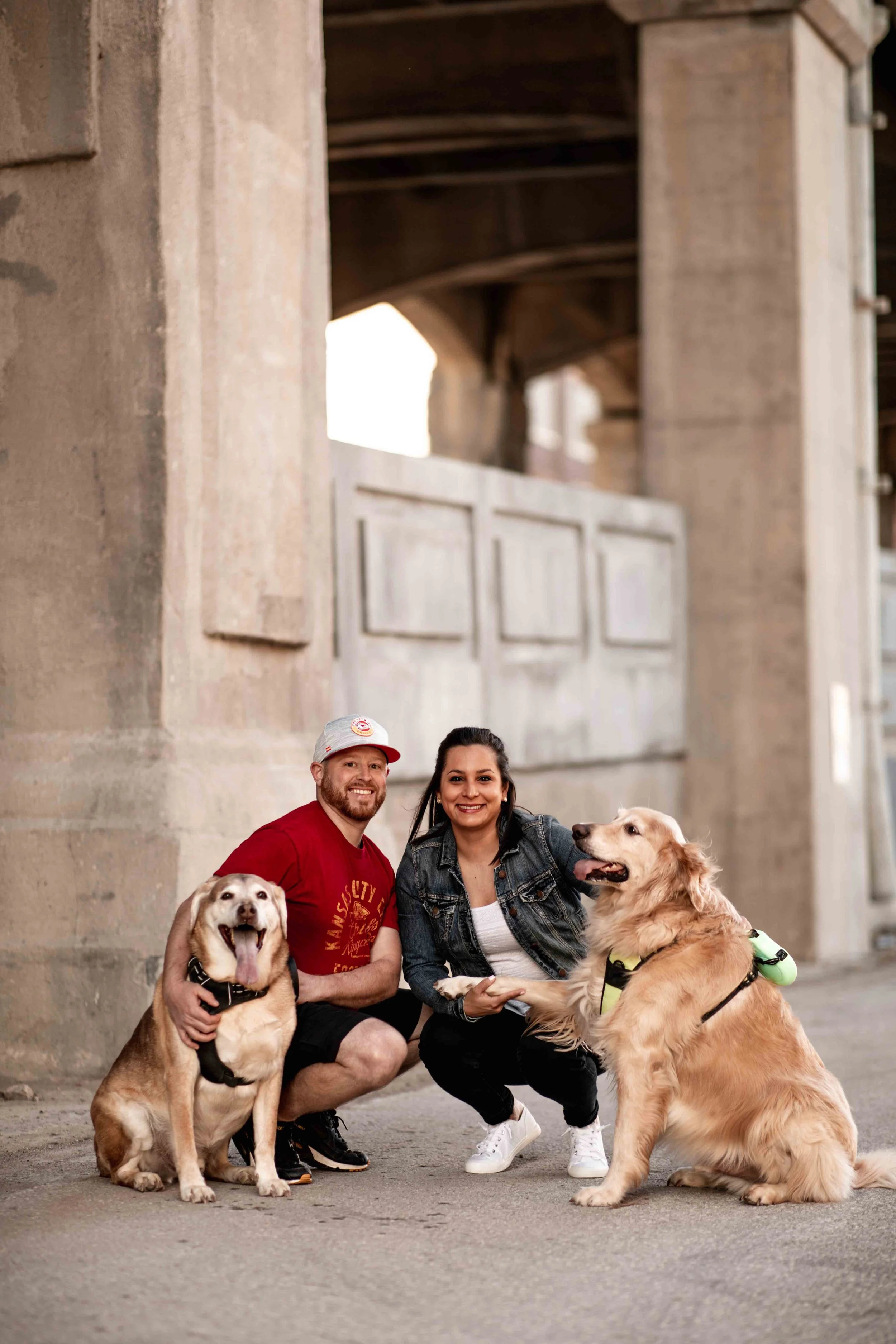 Engaged couple squatting with two dogs in the West Bottoms 