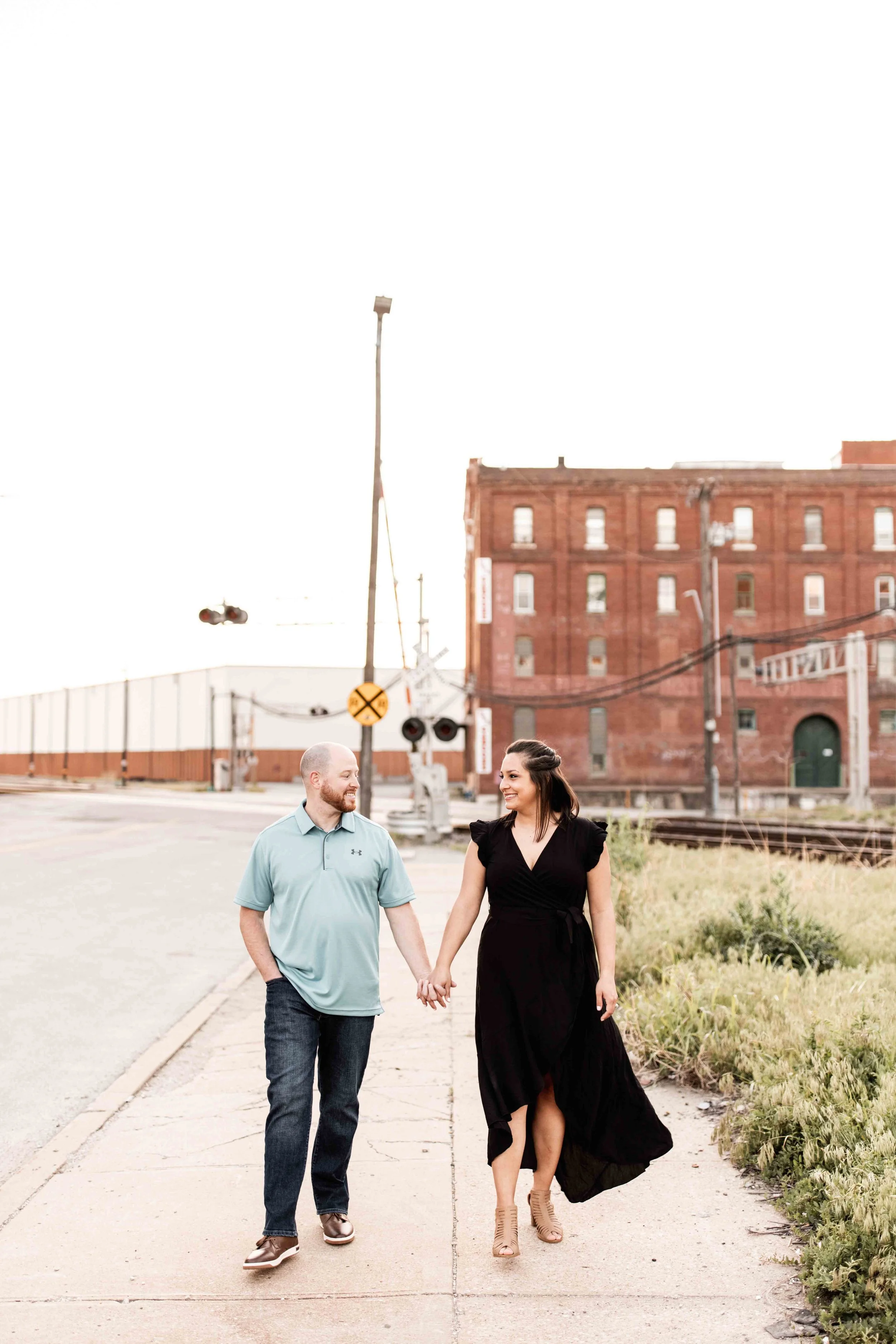 Engaged couple walking on the sidewalk in the West Bottoms area of Kansas City