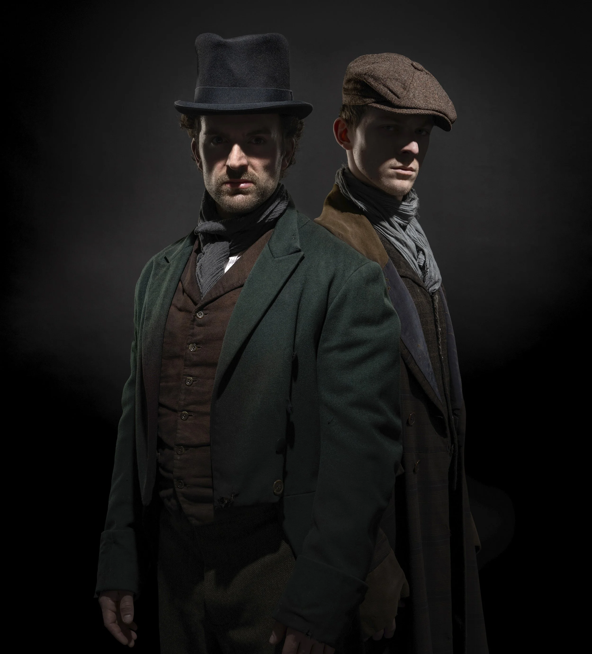 podcast cover image for the BBC's An Eye for a Killing. The two serial killers Burke and Hare stand on a dark background, moodily lit from above with their faces in shadow. dynamic entertainment portrait photography by Steve Bright London