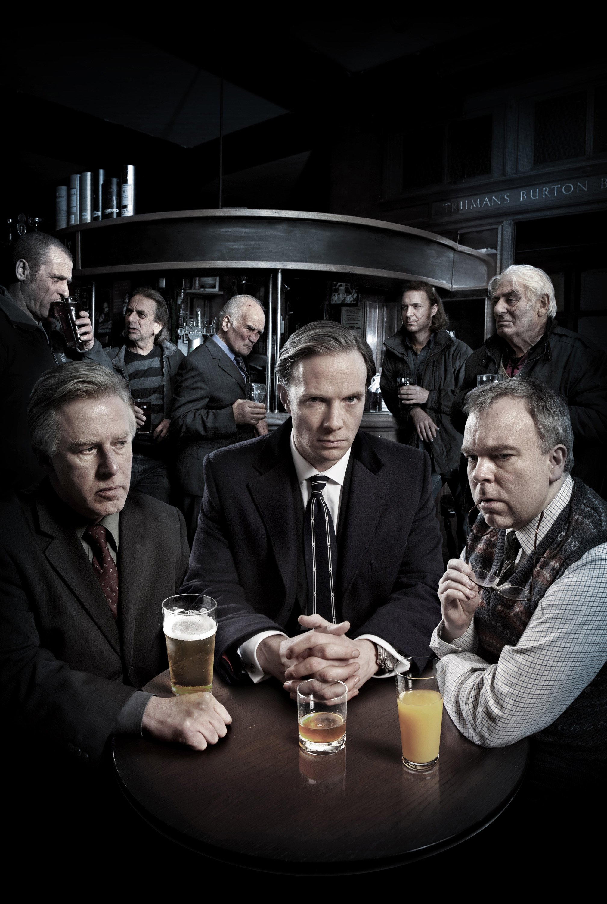 publicity image for the ITV detective drama Whitechapel. 	Rupert Penry-Jones Phil Davis and Steve Pemberton sit at a pub table, while various villainous characters lurk in the background. entertainment portrait photography by Steve Bright, London