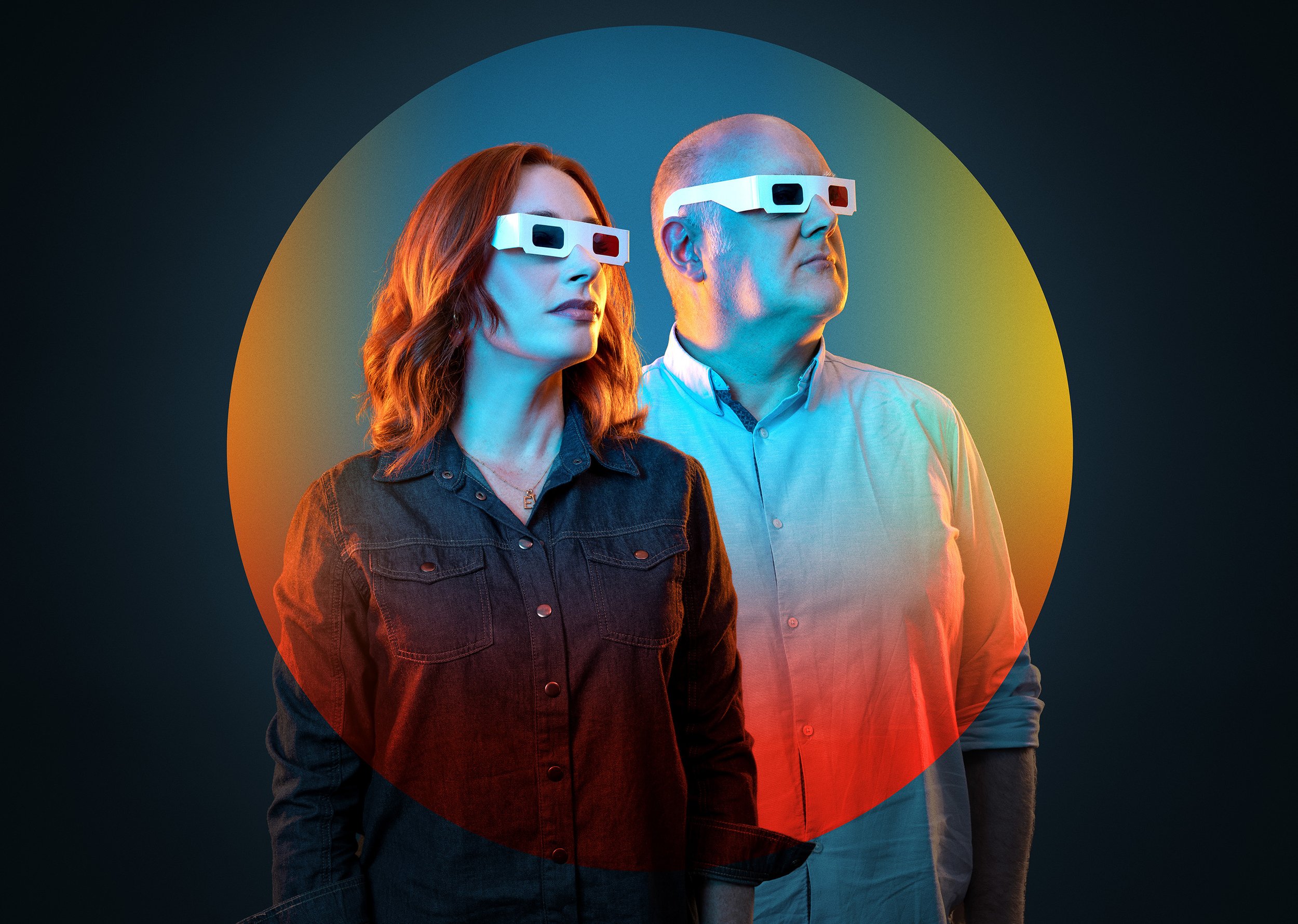 podcast cover image for the BBC podcast Curious Cases, showing Hannah Fry and Dara O'Briain standing in a coloured circle, lit with coloured light, wearing 3D glasses. dynamic entertainment portrait photography by Steve Bright London