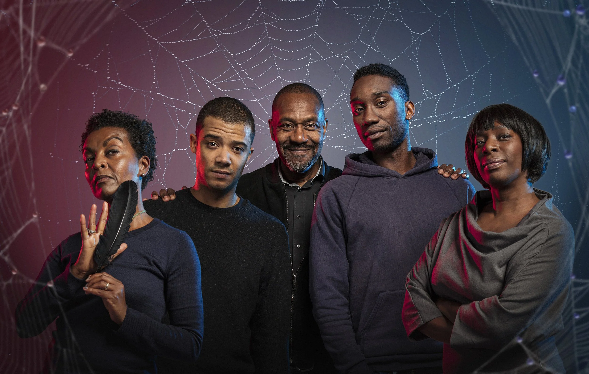 Promotional image of the  cast of Neil Gaiman's  Anansi Boys, for the BBC. The cast of the show stand surrounded by spider webs, lit with blue and red light. dynamic entertainment portrait photography by Steve Bright London