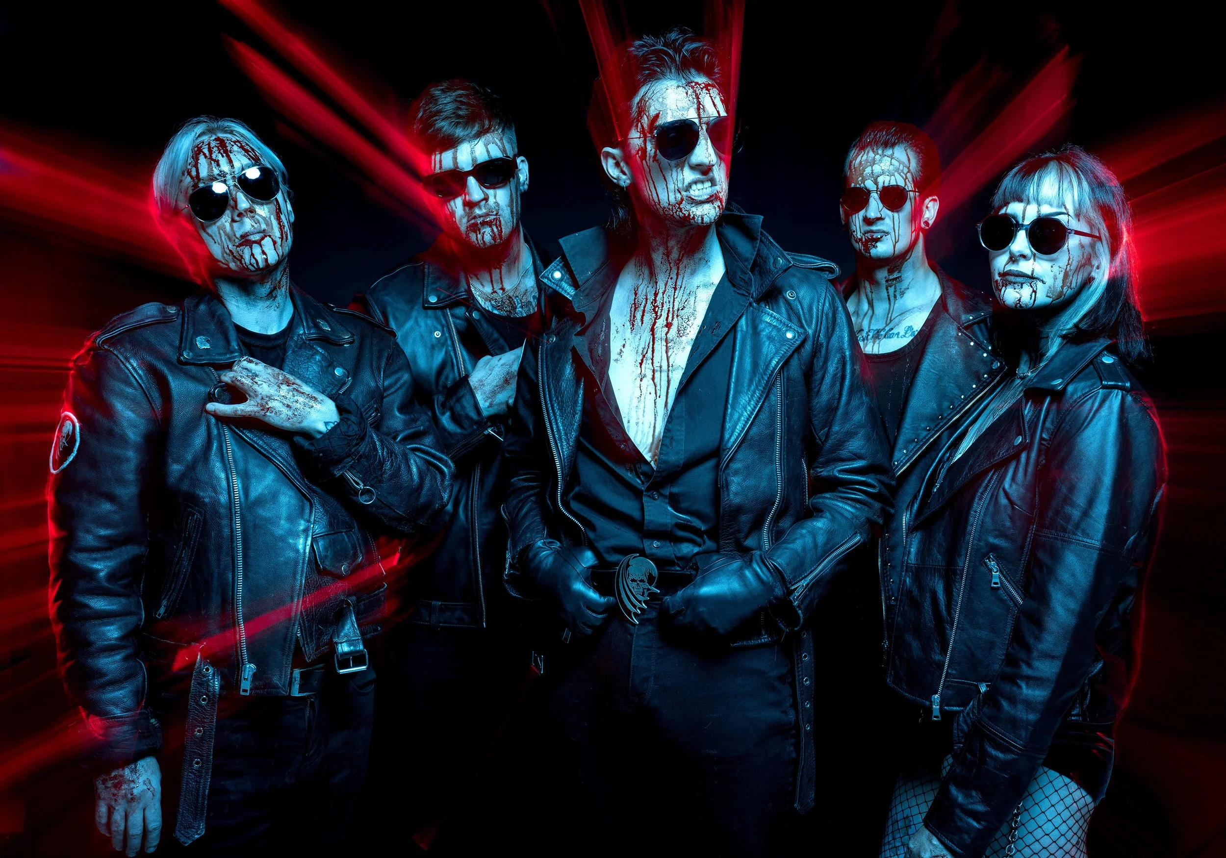 The rock band Creeper stand wearing leather jackets and sunglasses and with blood dripping down their faces, lit with blue light. Red rays of light emanate out from their bodies. dynamic entertainment portrait photography by Steve Bright London