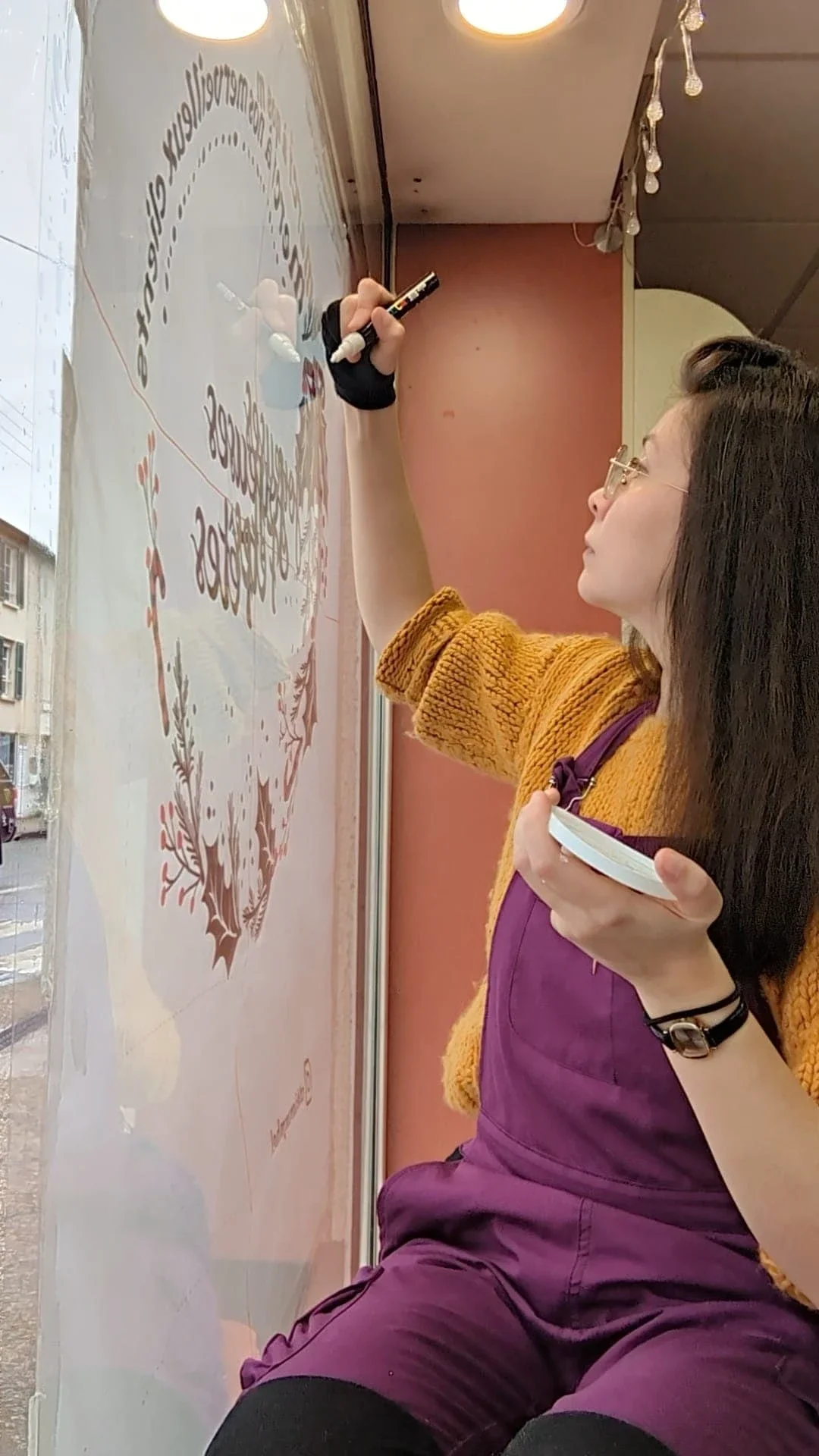 Peinture sur vitrine réalisée pour la pharmacie du Précoquet à Vaux sur-Seine (78). L'artiste Sandrine Daniel est en train de peindre la couronne de Noël.