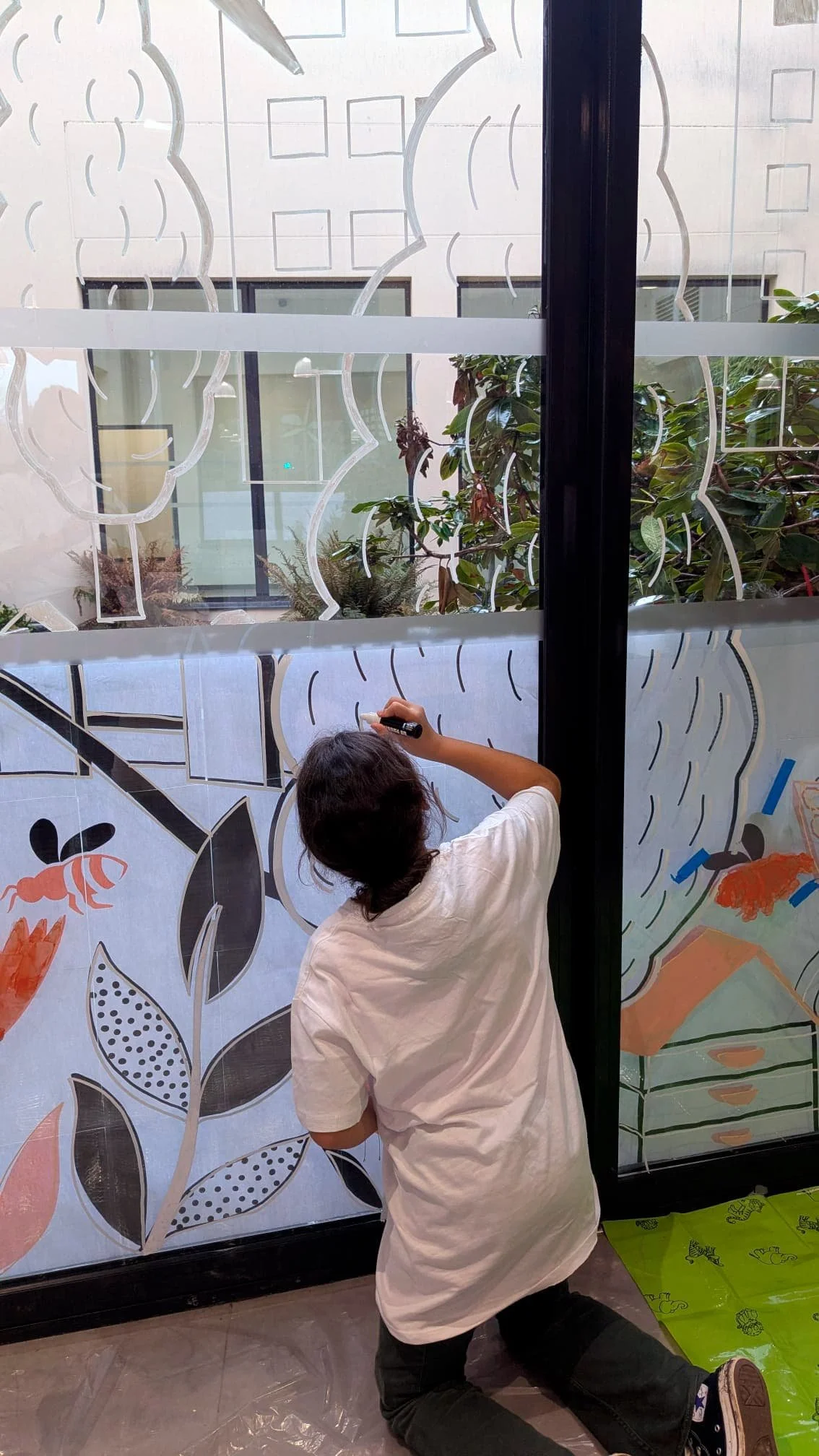 Fresque participative sur les vitrines du patio de la médiathèque des Mureaux, réalisée lors des Nuits de la lecture 2026. Thème "Villes et campagnes" — une soixantaine de participants, de tous âges. - Le public s'empare des différents outils : pince