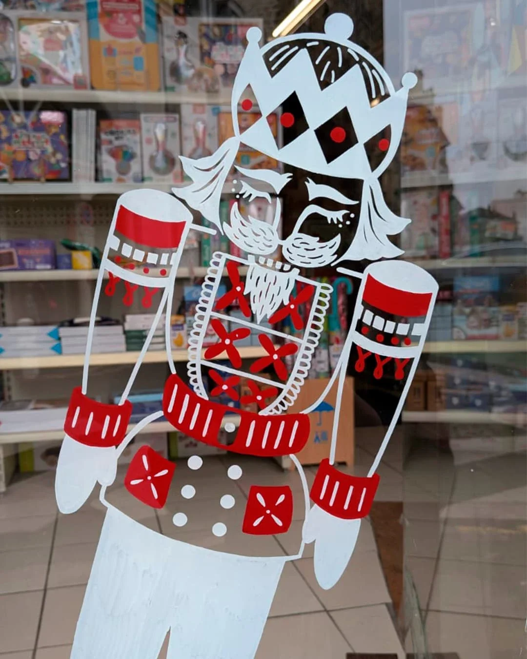 Peinture sur vitrine de Noël sur-mesure pour une boutique de jouets à Houilles (78), avec Casse-noisette, coloris blanc et rouge