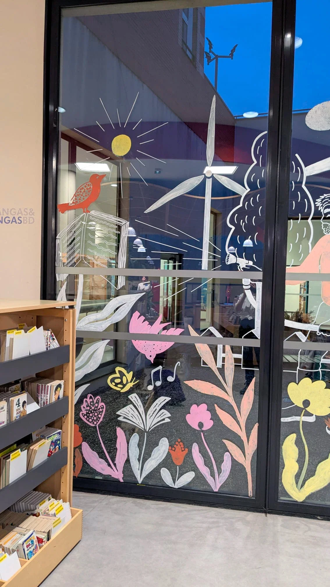 Fresque participative sur les vitrines du patio de la médiathèque des Mureaux, réalisée lors des Nuits de la lecture 2026. Thème "Villes et campagnes" — Panneau gauche