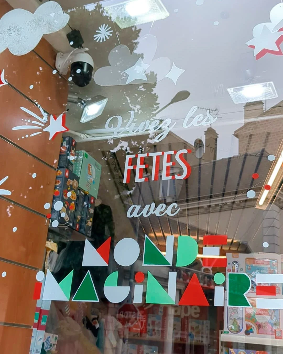 Peinture sur vitrine de Noël sur-mesure pour une boutique de jouets à Houilles (78), lettrage peint à la main, coloris blanc, rouge et verts