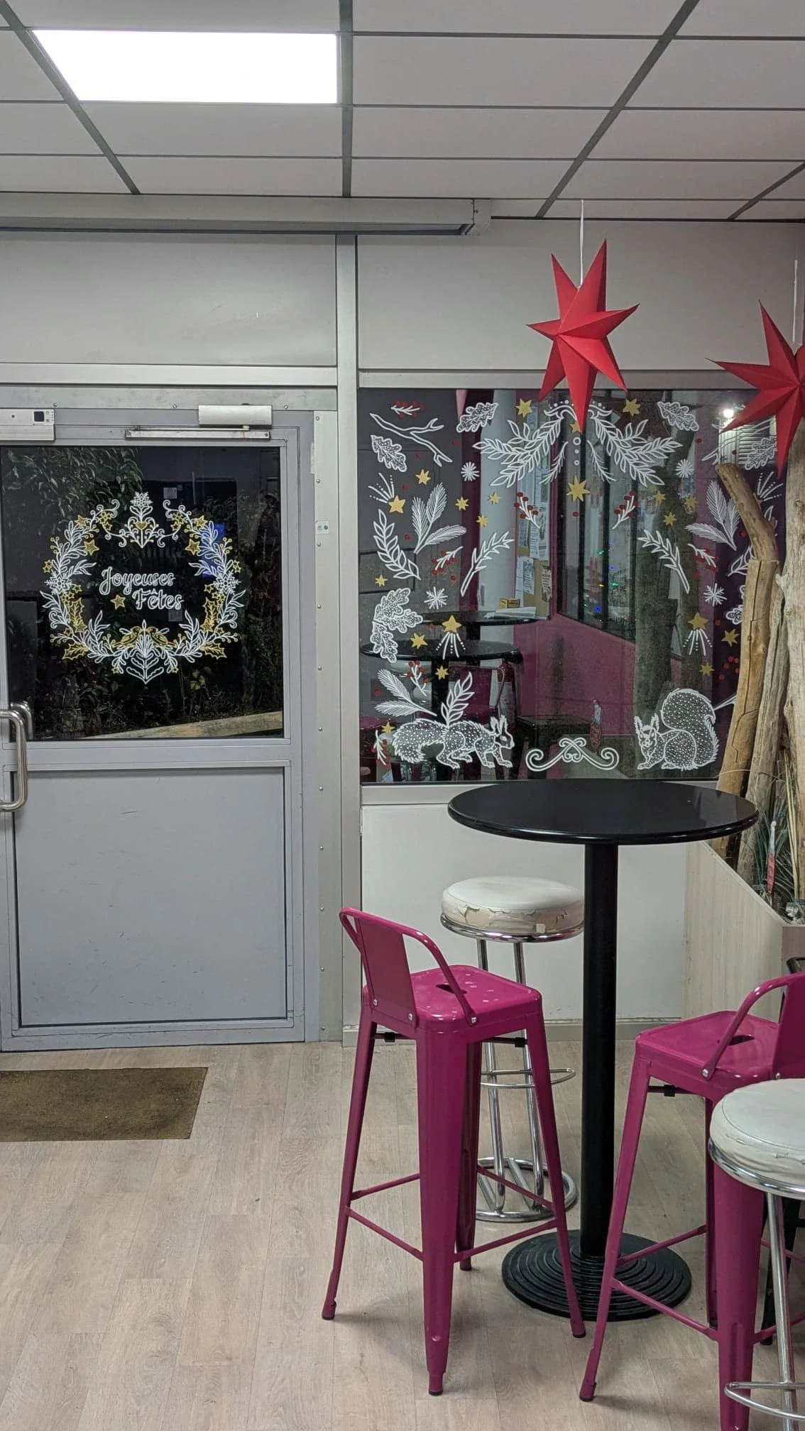 Décoration de Noël peinte à la main sur la porte et la fenêtre de l'espace café avec couronne, végétaux et écureuil