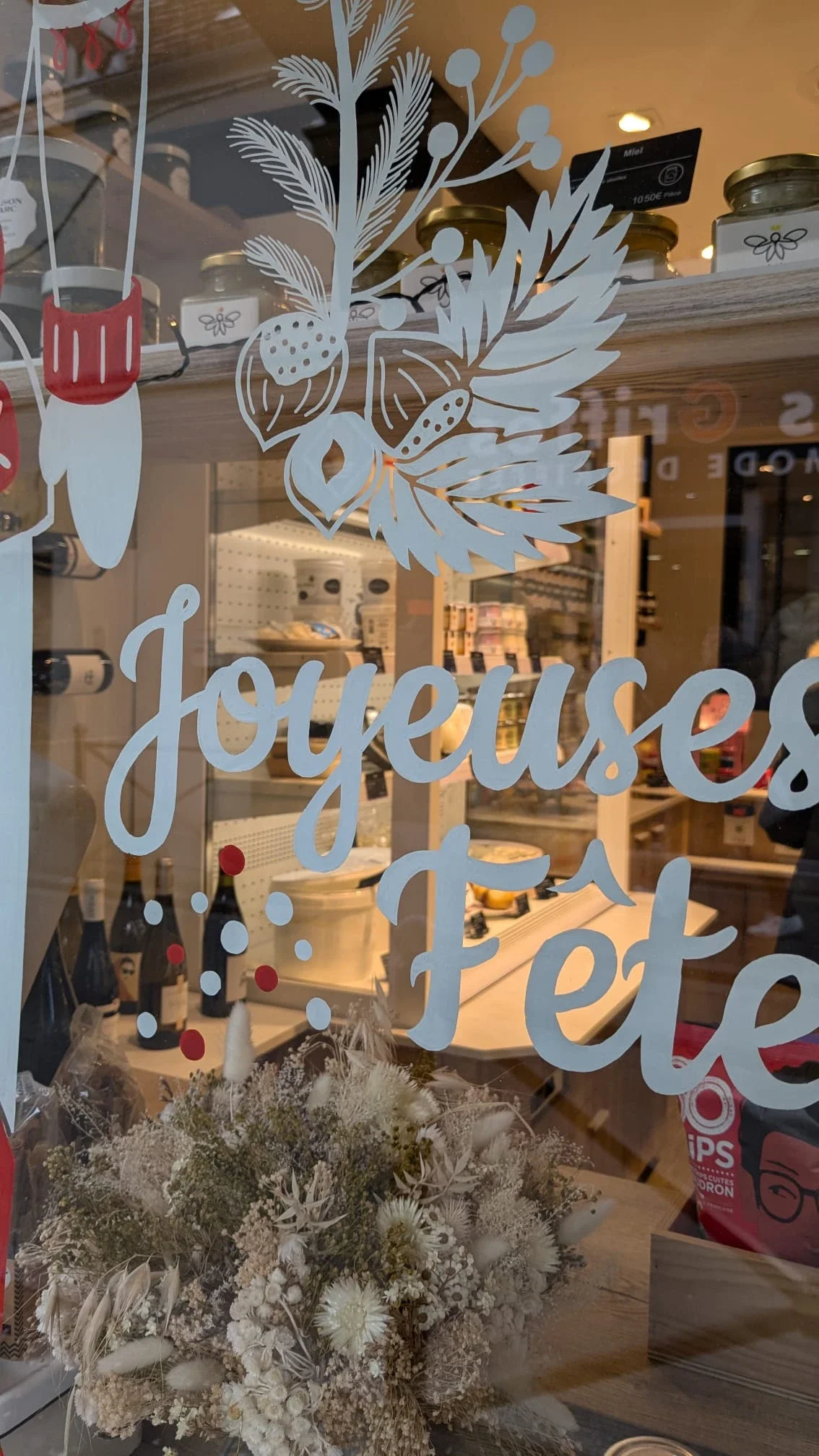 Détail du lettrage peint à la main « Joyeux Noël » sur la vitrine de Noël de la fromagerie Lallias à Houilles