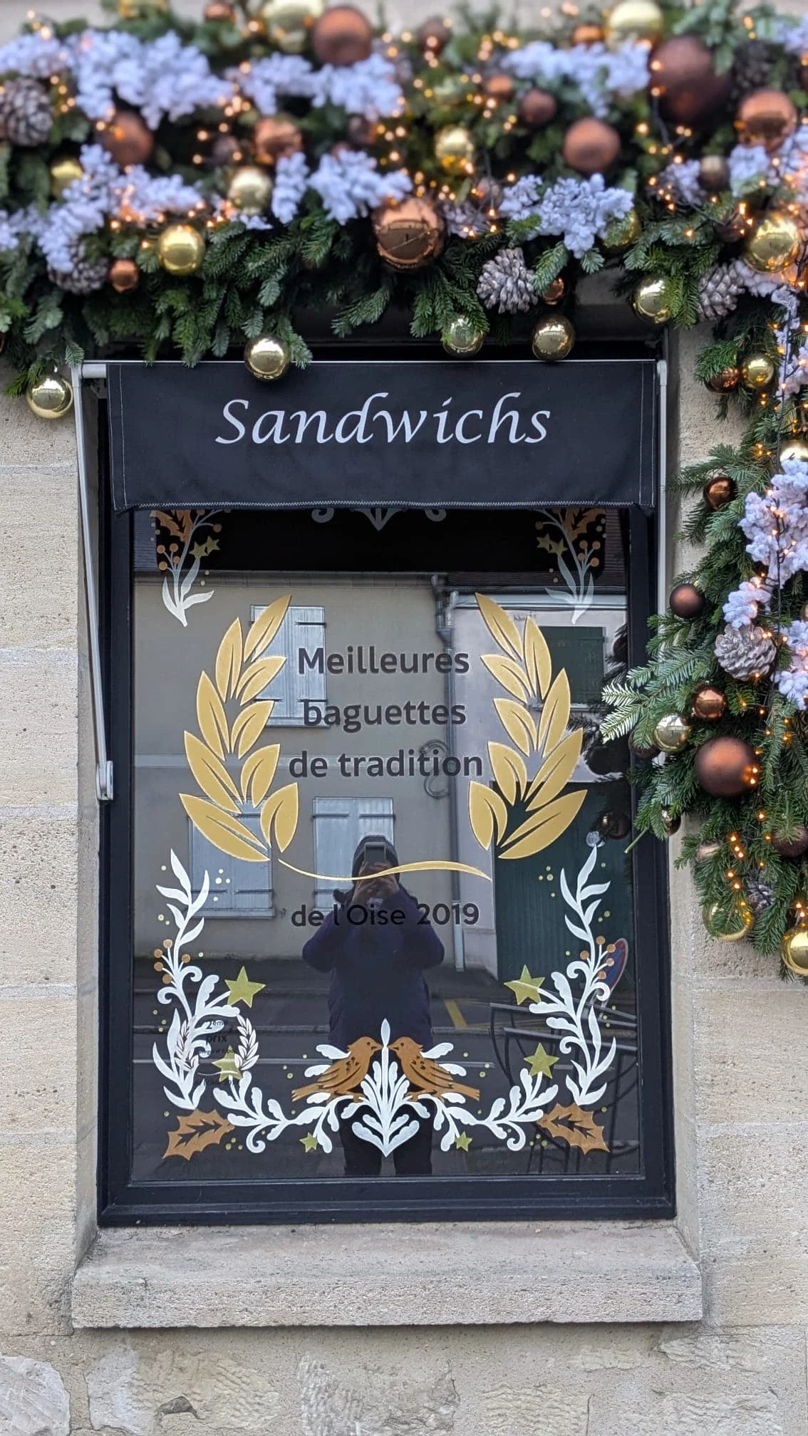 Peinture sur vitrine de Noël pour la boulangerie La Boulange à La Chapelle-en-Serval - frise d'encadrement sur la vitre droite - coloris blanc, doré et cuivré