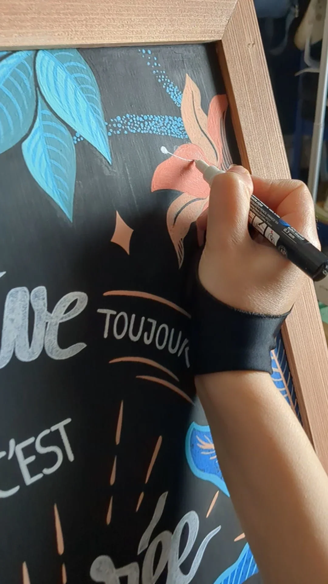 Gros plan sur la peinture des pistils d'une fleur de lys corail réalisée à la main sur une ardoise illustrée