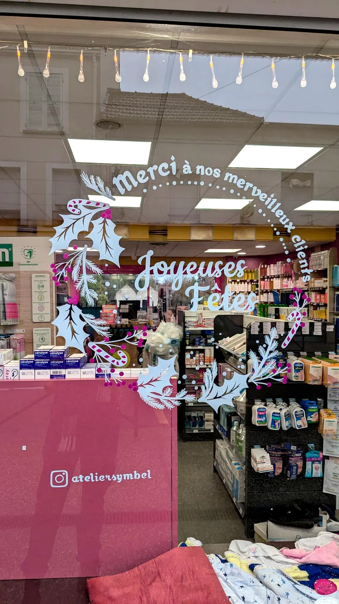 Gros plan sur la peinture sur vitrine de Noël représentant une couronne Houx et sucre de canne réalisée pour la pharmacie du Précoquet à Vaux-sur-Seine (78)