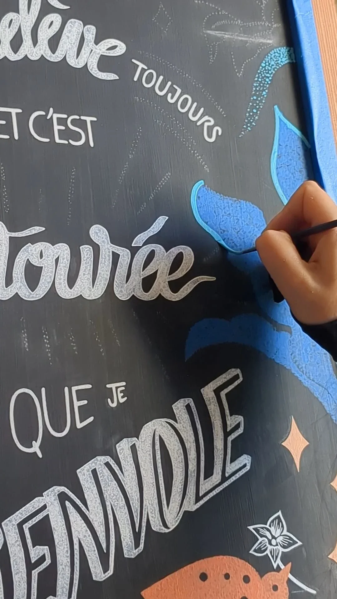 Application de rehauts bleu turquoise au pinceau sur un motif végétal peint à la main sur ardoise