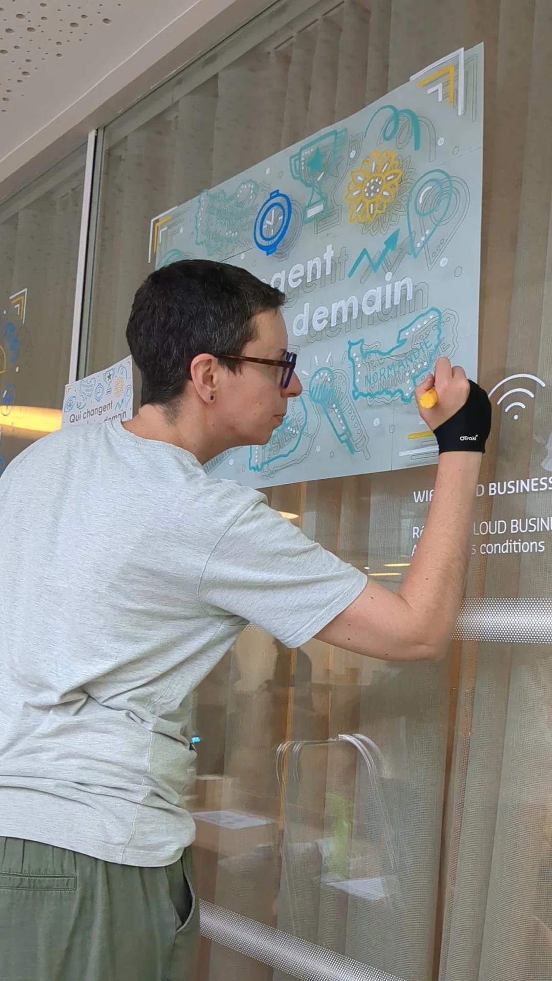 Camille Fauquet réalise à la main le visuel « Qui change demain » pour les vitrines des Trophées de l'innovation de l'Apec