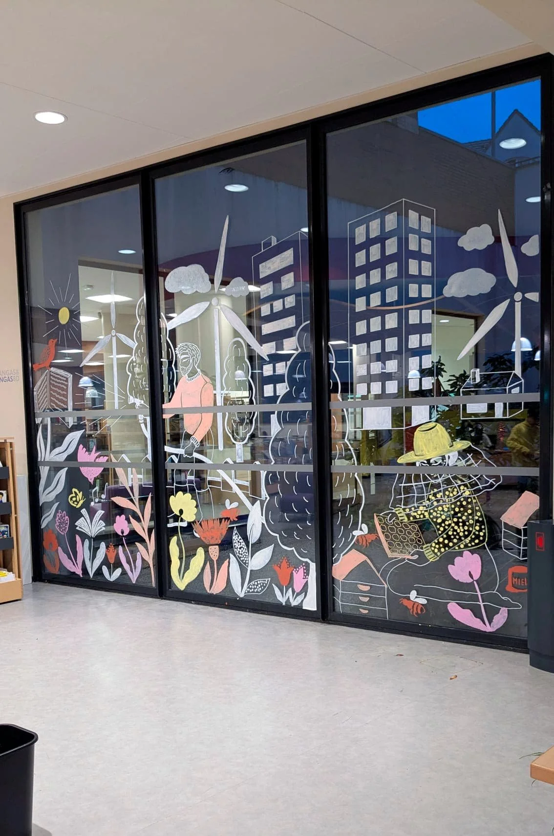 Fresque participative sur les vitrines du patio de la médiathèque des Mureaux, réalisée lors des Nuits de la lecture 2026. Thème "Villes et campagnes" — une soixantaine de participants, de tous âges. - Fresque terminée