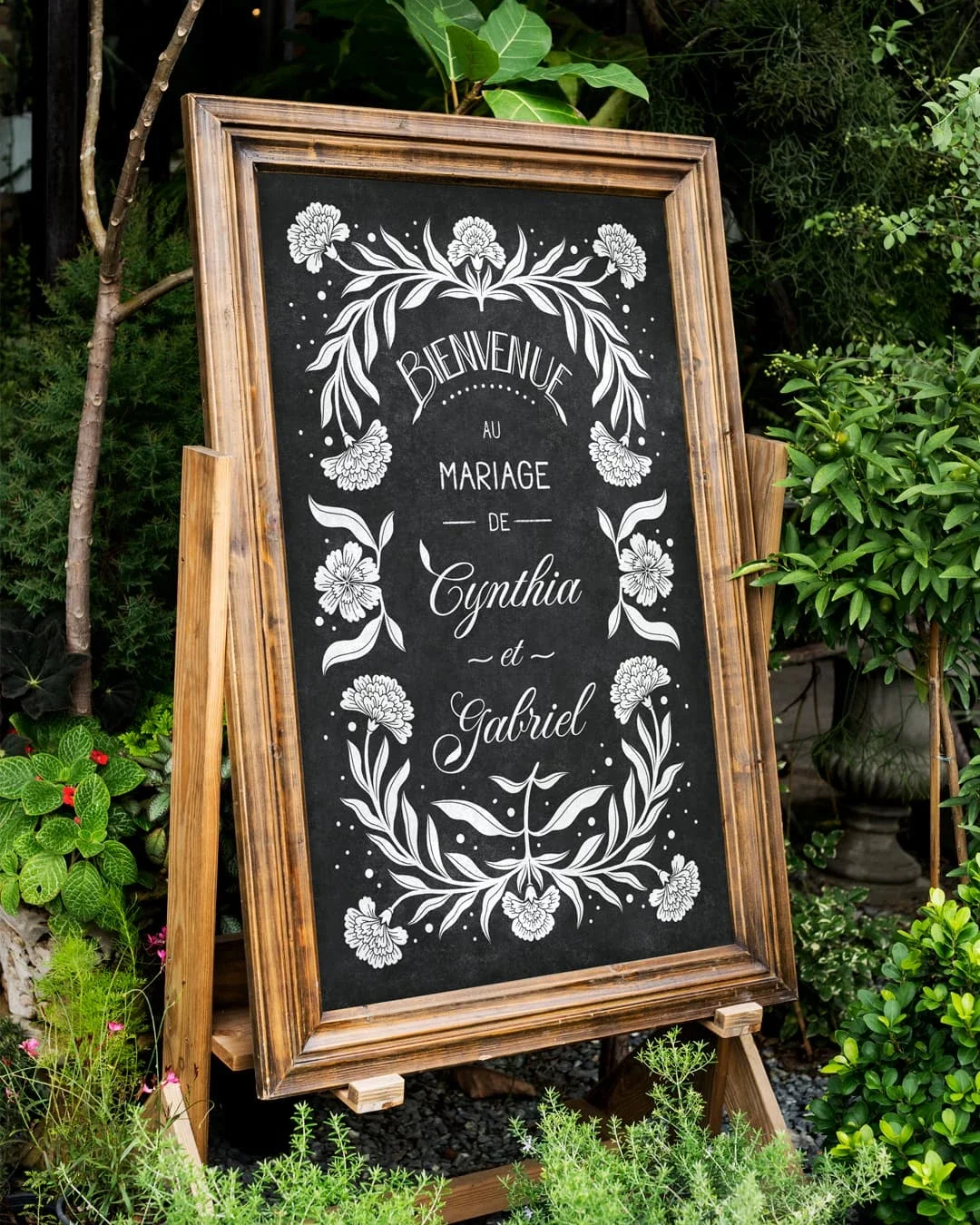 Ardoise illustrée peinte à la main. Panneau bienvenue mariage. Signalétique mariage. Coloris blanc. Frise florale avec des œillets. Message de bienvenue et prénoms des mariés.