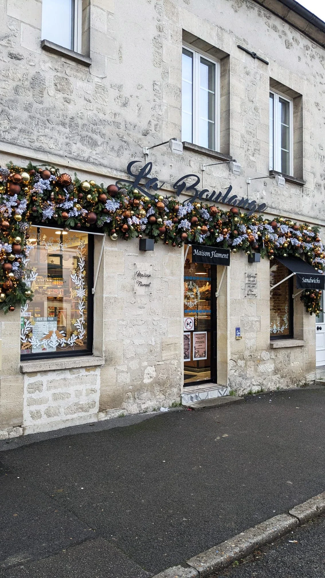 Peinture sur vitrine de Noël pour la boulangerie La Boulange à La Chapelle-en-Serval - une couronne sur la porte et de frise d'encadrement sur les fenêtres - façade