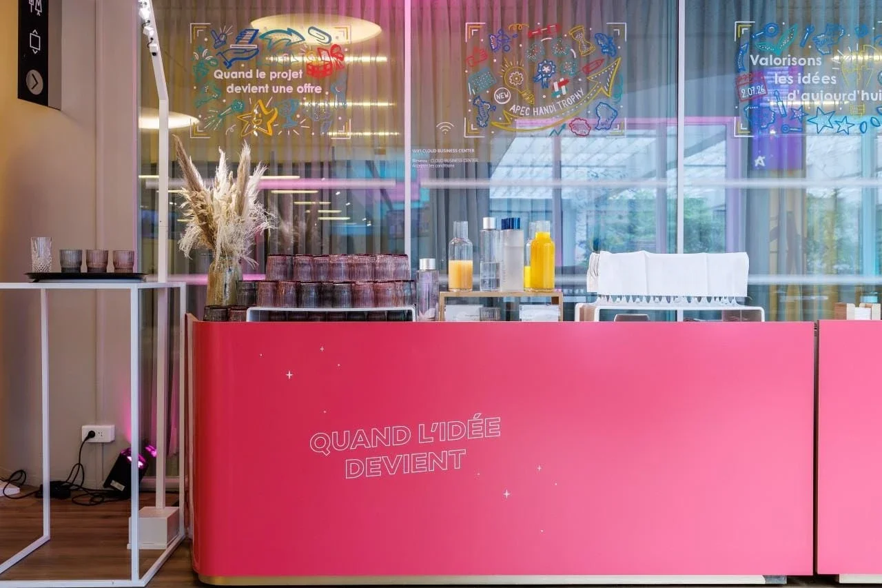 Comptoir de l'événement avec trois vitrines peintes à la main en arrière-plan lors des Trophées de l'innovation de l'Apec. Photo : Arnaud CAILLOU – Studio L'Œil Témoin