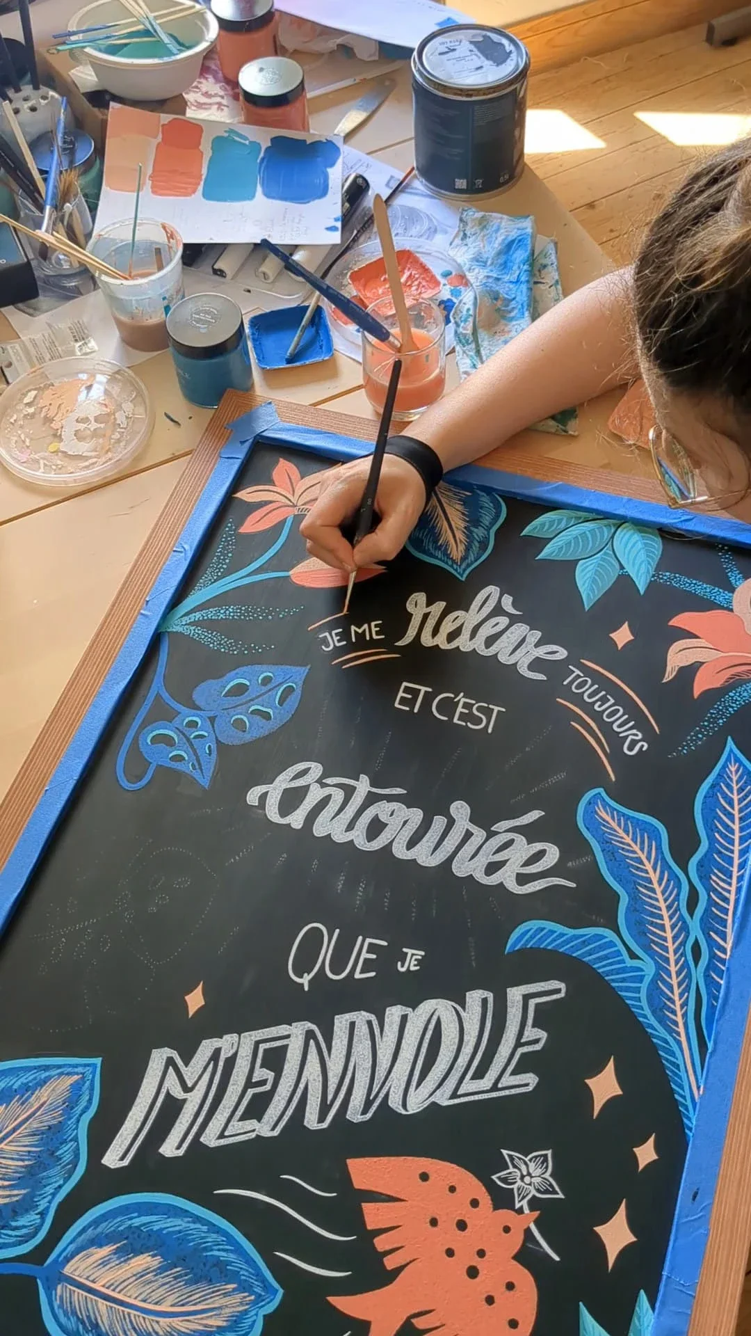 Sandrine Daniel souligne le lettrage du mantra positif avec des lignes décoratives. Création d'une ardoise illustrée peinte à la main