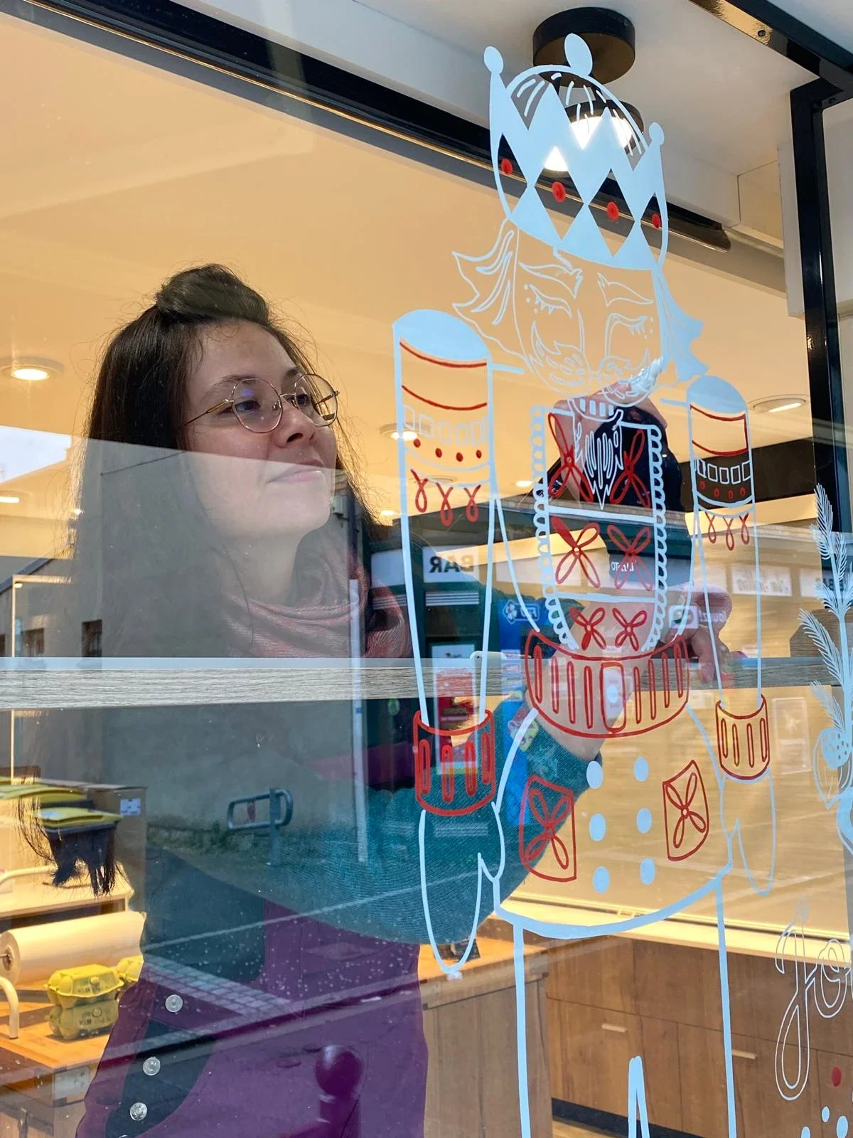 Sandrine Daniel réalise à la main une peinture sur vitrine de Noël représentant un Casse-Noisette pour la fromagerie Lallias à Houilles