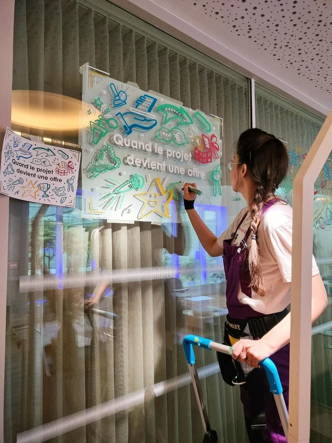 Sandrine Daniel peint à la main le visuel « Quand le projet devient une offre » lors de la préparation des Trophées de l'innovation de l'Apec