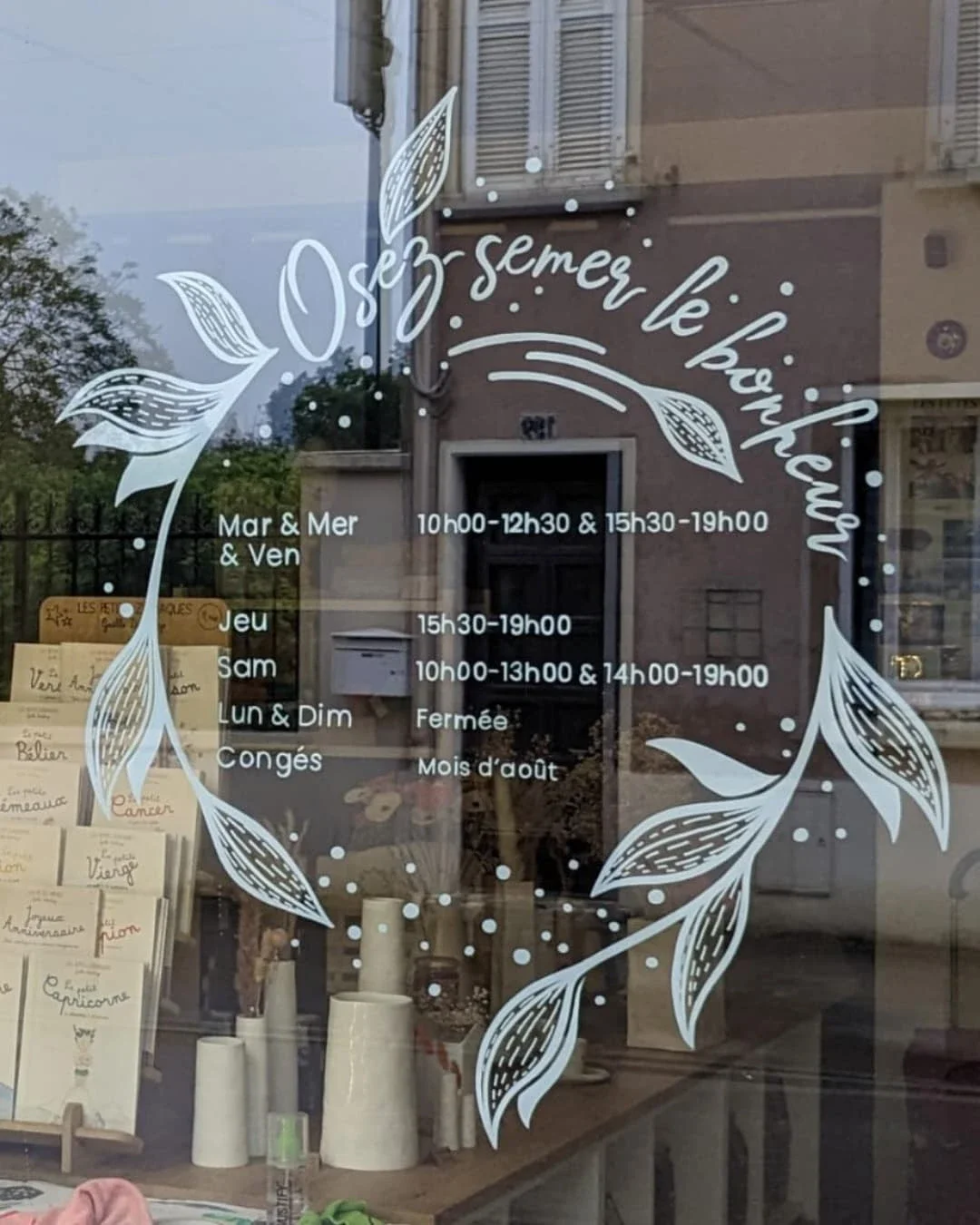 Peinture sur vitrine. Couronne d'horaires terminée avec lettrage pour une boutique de décoration à Houilles (78)