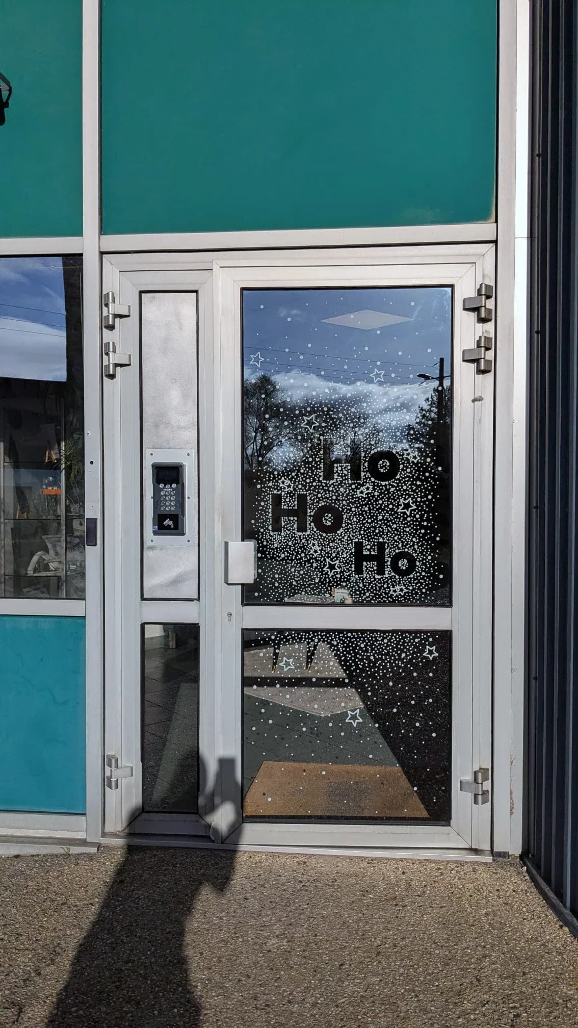 Détail de la porte de l'accueil de l'entreprise Vygon décorée d'une peinture de Noël peinte à la main avec le lettrage Ho ho ho.