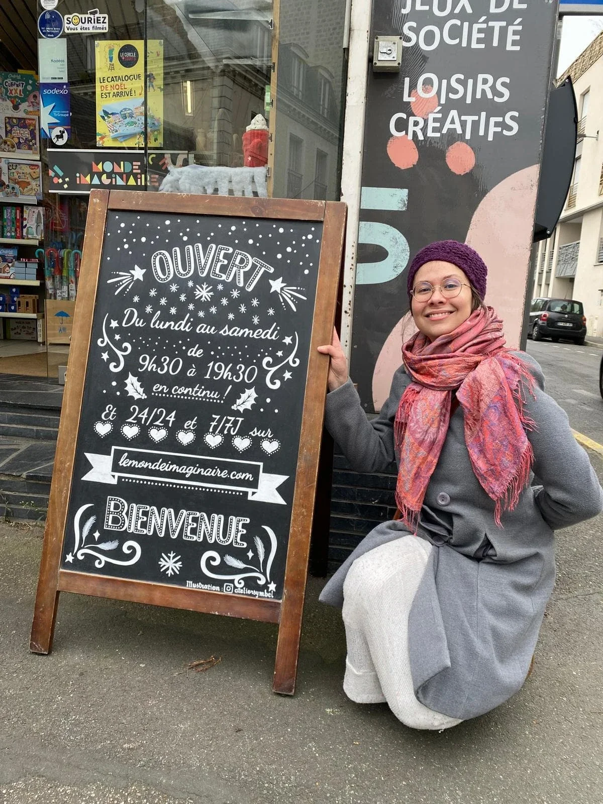 Sandrine Daniel à côté de l'ardoise terminée installée à l'entrée de la boutique de jouets Le Monde Imaginaire à Houilles (78)