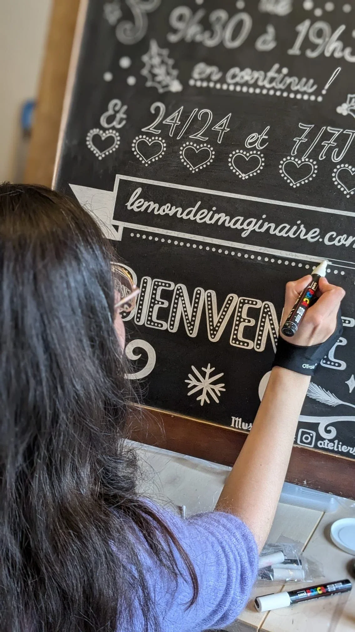 Sandrine Daniel peint à l'acrylique blanche le ruban décoratif sur une ardoise pour une boutique de jouets