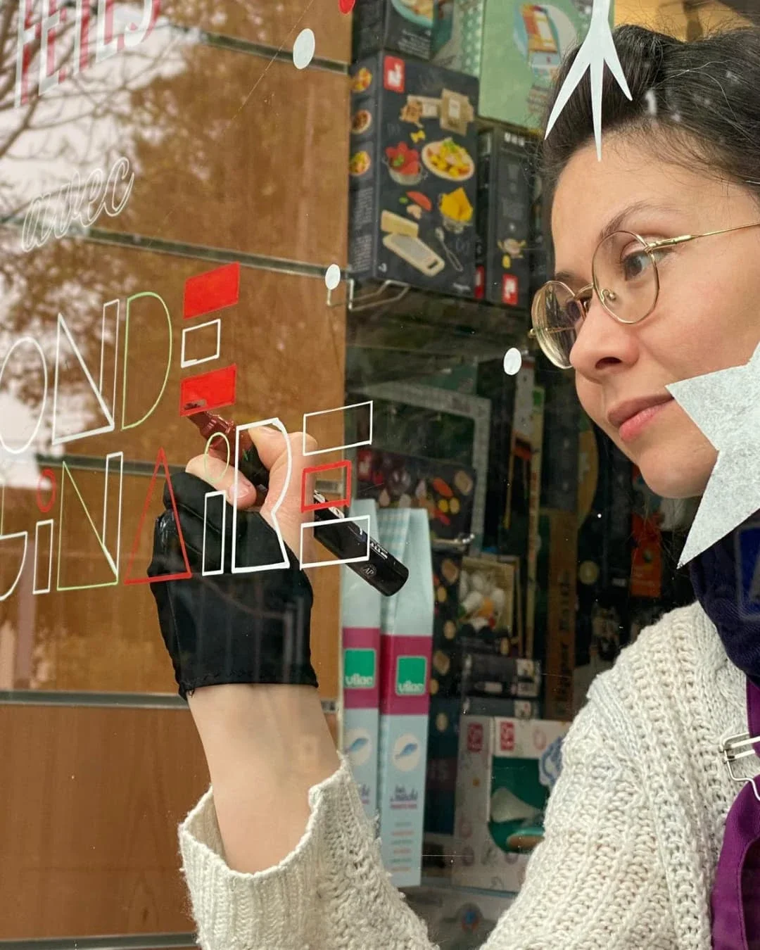 L'illustratrice Sandrine Daniel en train de peindre un lettrage sur une vitrine