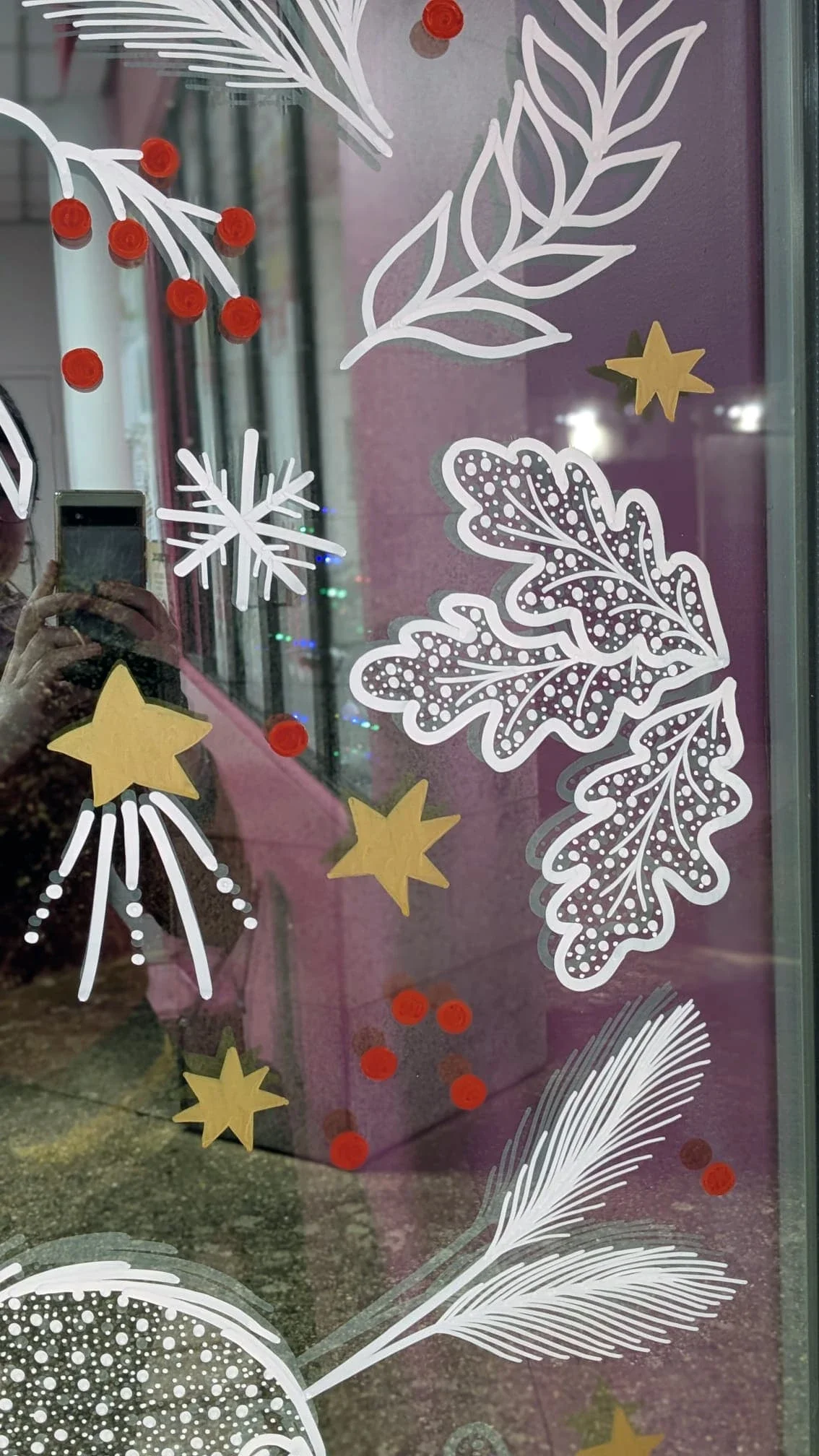 Détail des feuilles de chêne, baies rouges, végétaux et étoiles peints à la main sur la fenêtre de l'espace café du groupe Vygon à Ivry-le-Temple