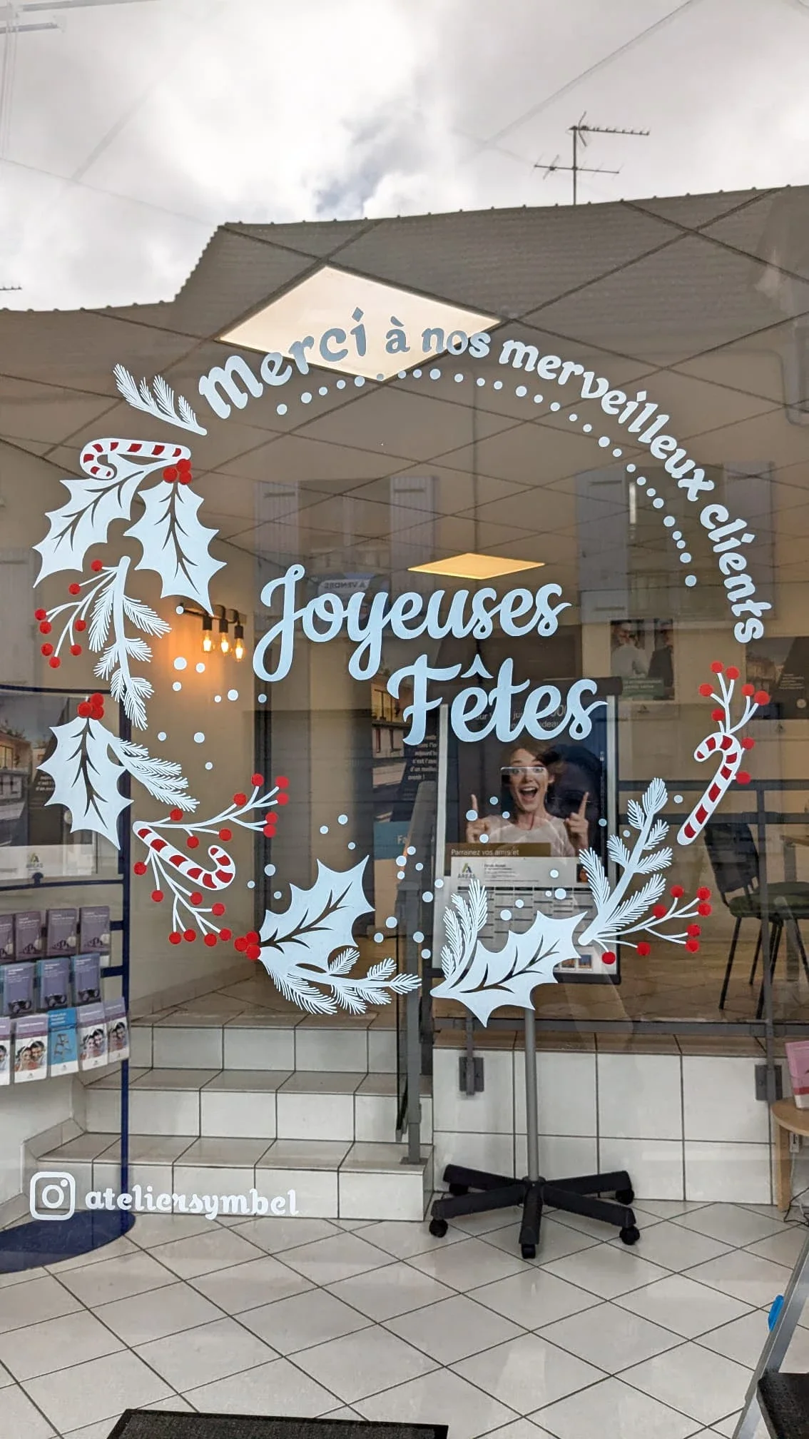 Gros plan sur la peinture sur vitrine de Noël représentant une couronne Houx et sucre de canne réalisée pour l'agence Aréas à Vaux sur-Seine (78)
