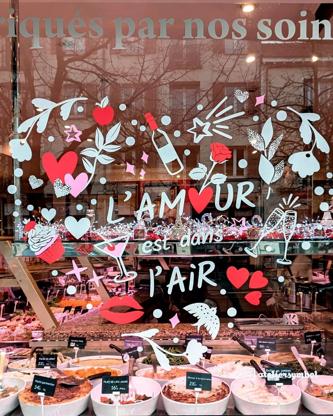 Peinture sur vitrine,  thématique Saint-Valentin, gros plan sur cœur Doodle avec lettrage "l'amour". Ensemble de fleurs, étoiles, bouteille de vin, oiseau, verre à cocktail, cupcake. Coloris blanc, rouge et rose