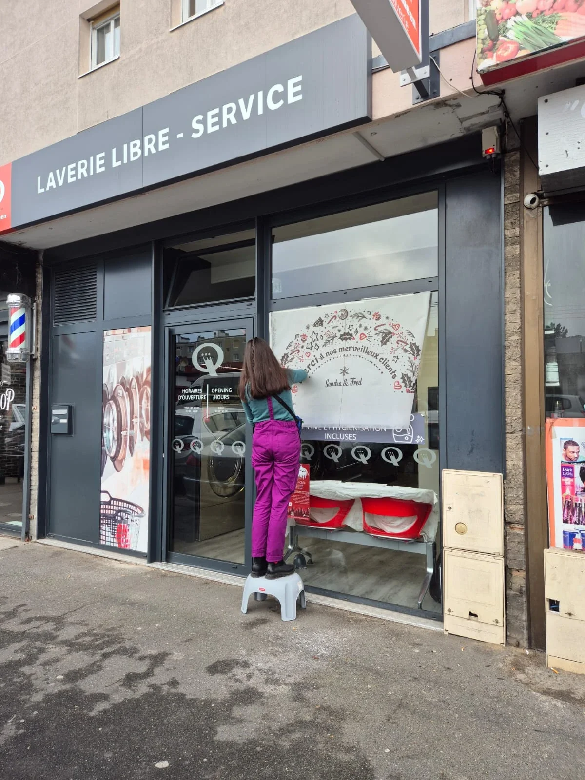 Sandrine Daniel prépare le chantier avant la réalisation d'une peinture sur vitrine de Noël pour une laverie à Sartrouville (78)